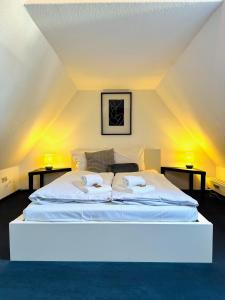 a large white bed in a room with two lamps at Galerie-Dachstudio- Ruhig & kompakt-Waschmaschine- WLAN- Parkplatz in Wolfsburg