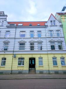 un edificio giallo e bianco con una porta di Großzügiges Apartment mit Balkon und 3 Schlafzimmern a Neumünster