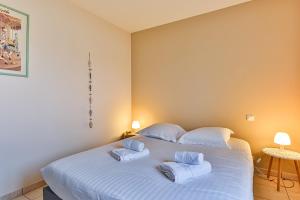 a bedroom with a large white bed with towels on it at Les Pinsons - Jardin - Parking - Wifi in Challans