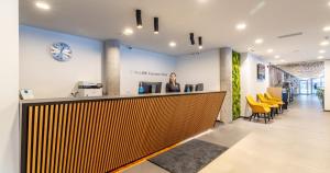 タリンにあるタリンク エクスプレス ホテルの黄色い椅子が置かれたオフィスのカウンターに立っている女性