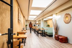 a woman walking through a restaurant with tables and chairs at Bloomhotel in Lochristi