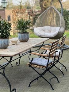 a wooden table with chairs and a swing at Sams Cottage in Roermond