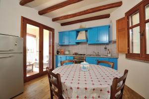 a kitchen with blue cabinets and a table with a table cloth at Villa Maddalena con parcheggio privato in Baunei