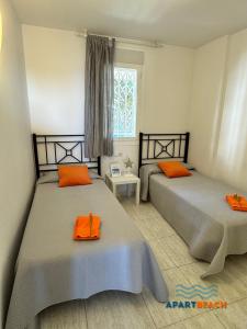 a bedroom with two beds with orange pillows and a window at APARTBEACH LA CALETA CLIMA y VISTAS CALA CRANCS in Salou +62 photos