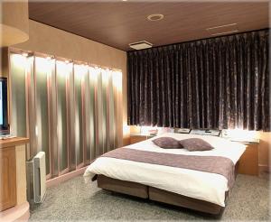 a bedroom with a bed with curtains and a television at HOTEL TWO in ONE Hiroshima-AdultOnly in Hiroshima
