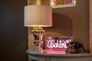 une lampe sur une table à côté d'un signe de néon dans l'établissement Purple Poppy Cottage, à Burton Joyce