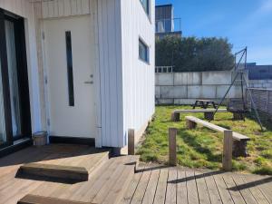 a building with a white door on a wooden deck at Modern leilighet med fin utsikt fra terrassen in Lillesand