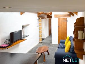 a living room with a blue couch and a tv at Ty Bedwen - Cosy Rural Retreat in St Davids in St. Davids
