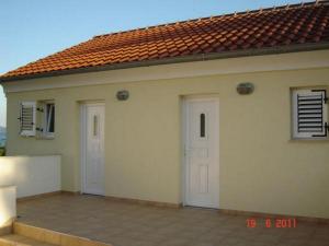 a house with two white doors and a red roof at Studio Apartments Darija in Brgulje