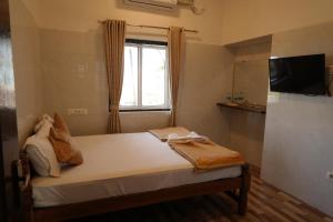 Un dormitorio con una cama con televisión y una ventana. en Amani Beach Homestay, en Māvalli