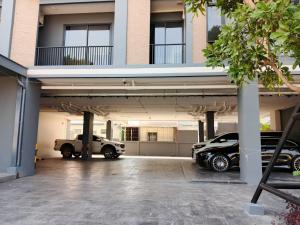 a building with two cars parked in a parking lot at The Richer Ratchaburi in Ratchaburi