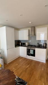 a kitchen with white cabinets and a stove top oven at St Leonards Boutique Apartment in Hollington