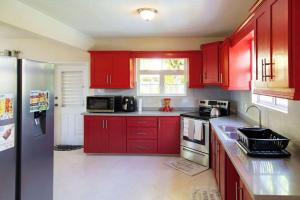 a red kitchen with red cabinets and a refrigerator at St Silas 3-bedroom by ZenBreak in Saint James +3 photos