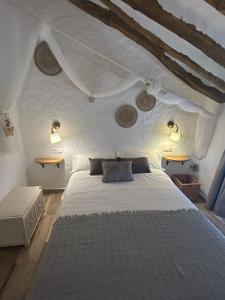 a bedroom with a white bed with two lights on it at Casa Las Tinajas in Iznájar