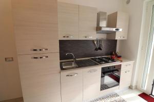 a kitchen with white cabinets and a sink and a stove at Casa Francesca Otranto Modern 3 Guest Flat with AC & WiFi in Otranto
