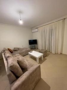Una sala de estar con un sofá y una mesa de café. en Andria Apartment, en Sarandë
