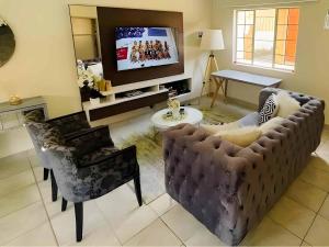ein Wohnzimmer mit Sofa und Fernseher in der Unterkunft Capricon Village 3 Bedroom Villa in Centurion