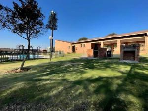 ein Gebäude mit einem Baum vor einem Hof in der Unterkunft Capricon Village 3 Bedroom Villa in Centurion