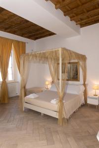 a bedroom with a canopy bed and two windows at Le Boutique Luxury Rooms diffused in Historic Center in Fiumicino