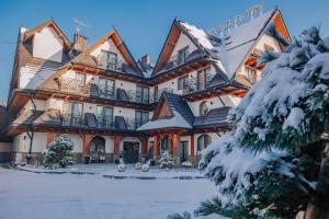 a large building with snow on the ground at Grand Tatry - miejsce na wyjątkowy pobyt dla Ciebie i Twojej rodziny! - sauna i jacuzzi wliczone w cenę pobytu - 10 minut pieszo od Term Bania in Białka Tatrzanska