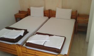 two beds in a room with white sheets and towels at Pension Kyriakos in Plakias