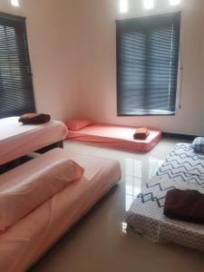 a room with three beds and two windows with blinds at MULYA HOMESTAY Syariah in Sampang