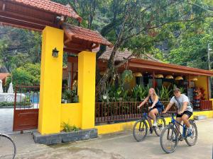 For You Ninh Binh Boutique في نينه بينه: شخصان يركبان الدراجات أمام مبنى أصفر