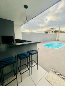 a bar with stools in front of a swimming pool at Casa com piscina Bauru SP in Bauru