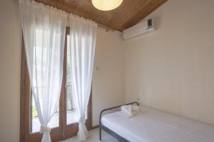 Schlafzimmer mit einem Bett und einem Fenster mit weißen Vorhängen in der Unterkunft Eria Home by RentalsPro - Trikorfo Halkidiki in Yerakiní