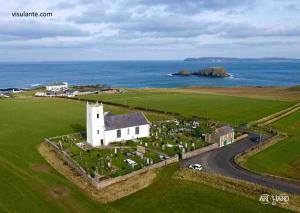 an aerial view of a white church with the ocean at Ballintoy old school house in Ballintoy