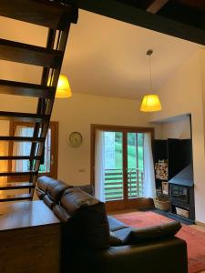 een woonkamer met een leren bank en een trap bij La Molina Alp c Puigmal in Girona