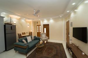 a living room with a blue couch and a tv at Oscar Apartment ! 5 ! in Jazīrat al ‘Awwāmīyah