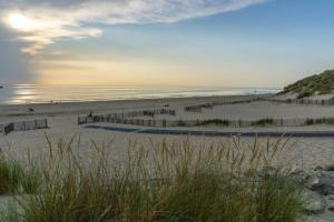 a beach with people walking on the sand and the ocean at La CABANE d'Arthur in Camiers
