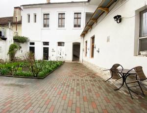 un banc assis devant un bâtiment blanc dans l'établissement Piața Sfatului Brassai Apartments, à Braşov