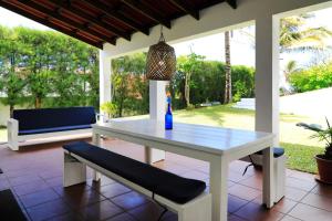 a white table and a bench on a porch at Casa das Palmeiras - Palm Tree House in Ponta do Ouro