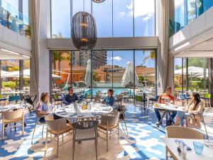 a group of people sitting at tables in a restaurant at Novotel Monte-Carlo in Monte Carlo