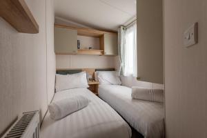 two beds in a small room with a window at St Andrews Holiday Park - Kinkell Braes No 16 in St. Andrews