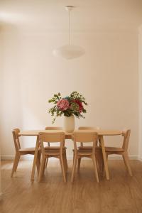 einen Tisch mit Stühlen und eine Vase mit Blumen in der Unterkunft CASA SIRFANTAS Málaga in Málaga