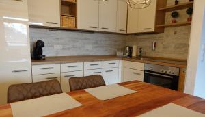 a kitchen with white cabinets and a wooden table at Panorama Apartment in Bad Harzburg