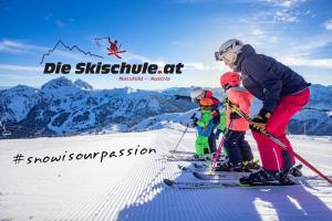 a woman and two children on skis in the snow at Apartment Hotel Schneerose in Sonnenalpe Nassfeld