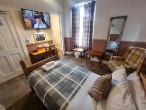 a bedroom with a bed and a chair and a mirror at Roy Bridge Hotel in Fort William