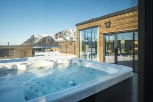 a hot tub in front of a building with mountains at Arctic Serenity Lodge Lofoten - jacuzzi & sauna LL12 in Lyngværet