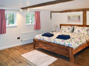 a bedroom with a bed and two windows at Rose Cottage in Bethersden