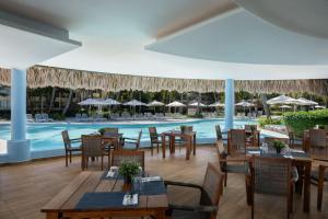a restaurant with a pool and tables and chairs at Impressive Punta Cana - All Inclusive in Punta Cana