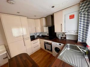 a small kitchen with white cabinets and a sink at Bull Double bed in shared house in Stifford
