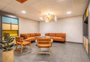 - une salle d'attente avec des canapés, une table et des chaises dans l'établissement B&B HOTEL Marseille Les Ports, à Marseille