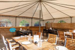a marquee with wooden tables and chairs in a tent at Camping Paradis Vallée du Lot in Pujols