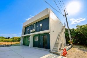 un edificio con puertas verdes y escaleras. en プラスライフ白保, en Ishigaki Island