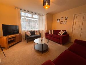 a living room with a red couch and a tv at Maple House in Bristol