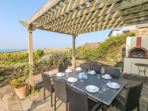 a table and chairs on a patio with a pergola at Coastman's Nest in Newquay